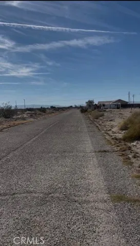 Paved road in front of the property with home to the left of property.