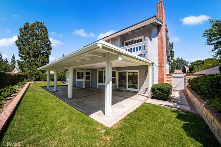 View of backyard, covered patio and lawn. Slider from Great Room to patio and Primary Suite balcony.