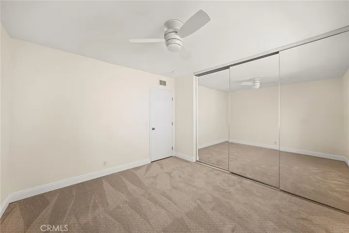 Second upstairs bedroom with mirrored wardrobe door and ceiling fan with light.