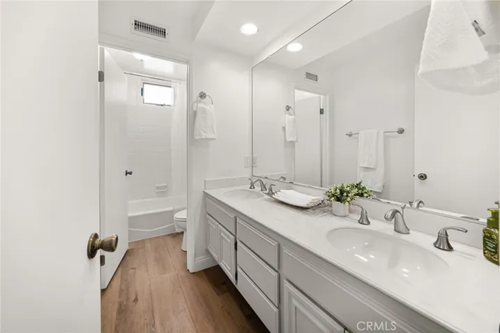 Hall bathroom with dual sinks. Separate shower/tub and toilet area.