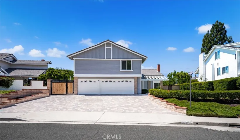 Front view of property with custom paver driveway, lots of parking and mature landscaping.