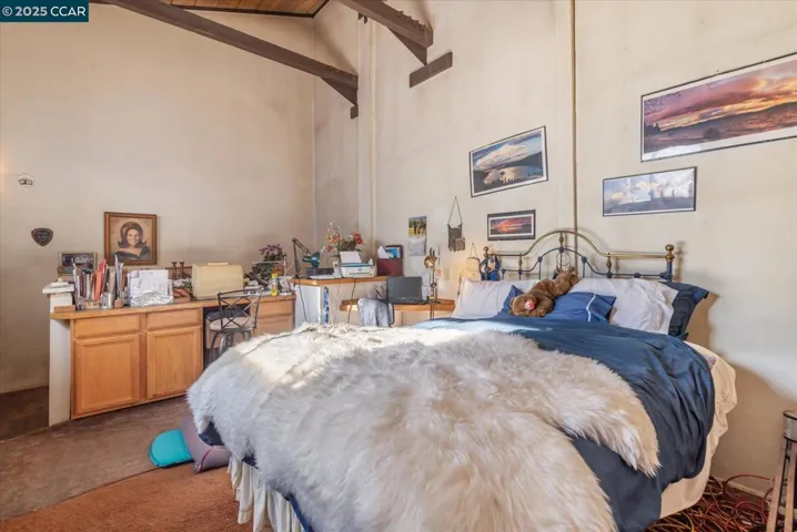 Spacious loft-style primary suite with soaring ceilings, exposed beams, and versatile space for a sitting area or home office.