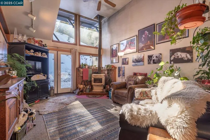 Soaring ceilings and expansive windows fill the living room with natural light, complemented by a cozy wood-burning stove for mountain evenings.