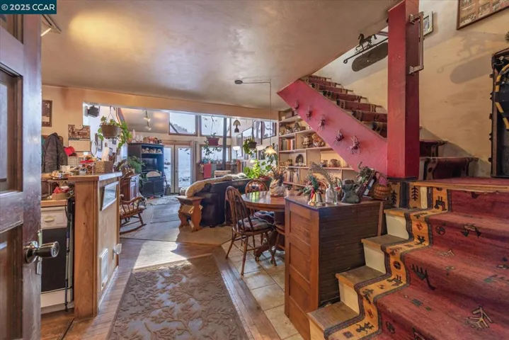 Welcoming entry opens into the dining area and main living space, featuring built-in shelving and rustic accents under the staircase.