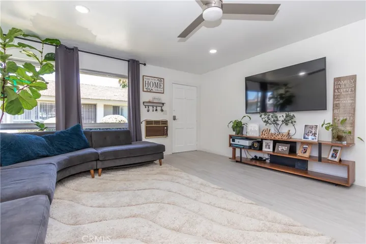 Gorgeous living room with large windows, porcelain wood style tile floor, recessed lighting and fan.