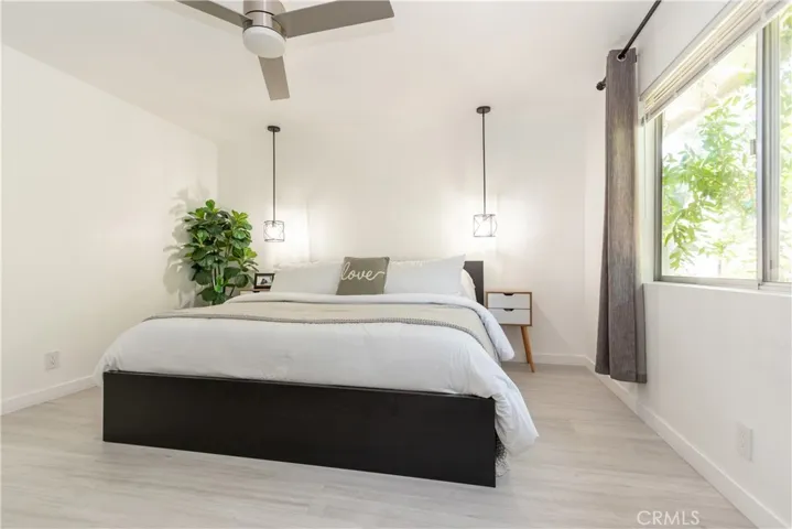 Spacious primary bedroom with lovely natural light and green view.