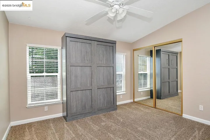 Unfurnished bedroom featuring carpet, multiple windows, a closet, and vaulted ceiling