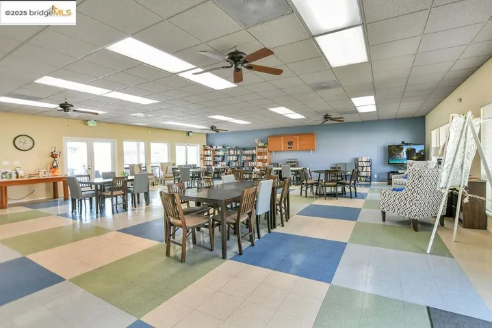 Dining room featuring a ceiling fan, a drop ceiling, and tile patterned floors