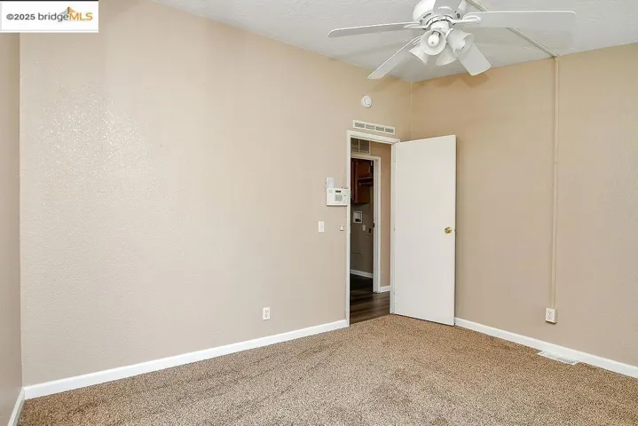 Carpeted spare room with a ceiling fan and baseboards
