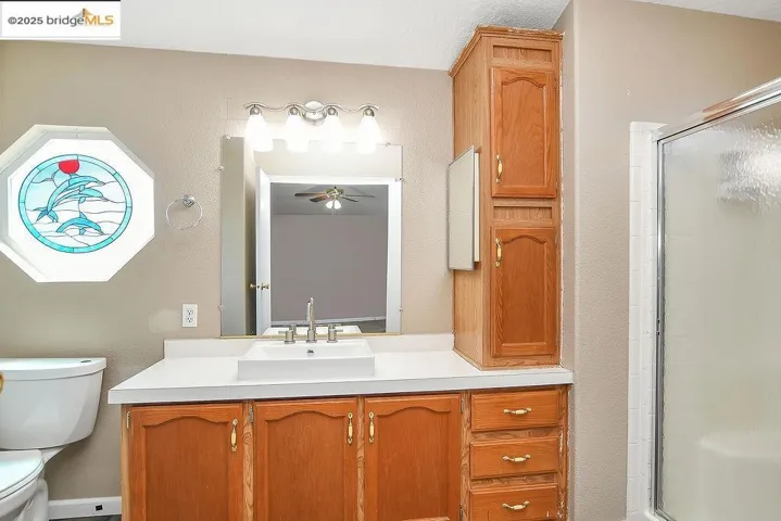 Bathroom with vanity, a stall shower, ceiling fan, and a textured wall