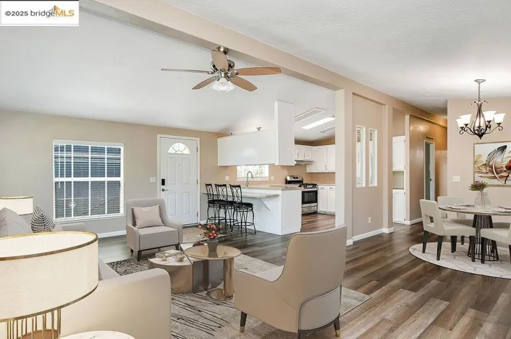 Living area featuring dark wood-style flooring, a chandelier, and a ceiling fan