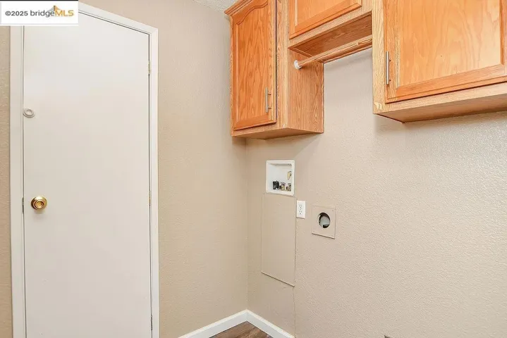 Laundry room featuring washer hookup, cabinet space, electric dryer hookup, wood finished floors, and a textured wall