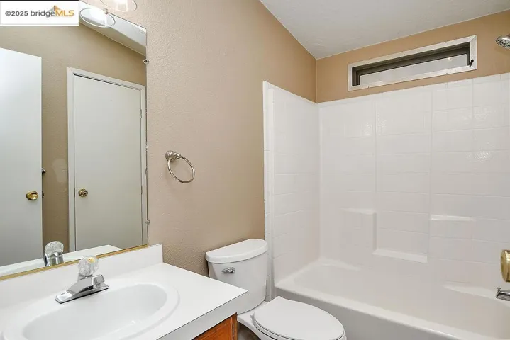Bathroom featuring a textured wall, vanity, and shower / washtub combination