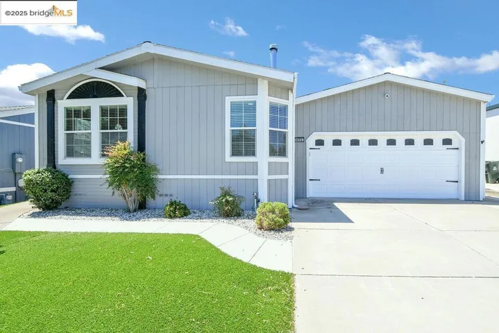 Manufactured / mobile home featuring driveway, a front lawn, and a garage
