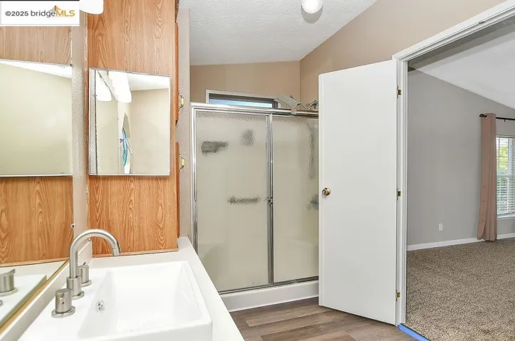 Full bathroom featuring a stall shower, a textured ceiling, wood finished floors, and vanity