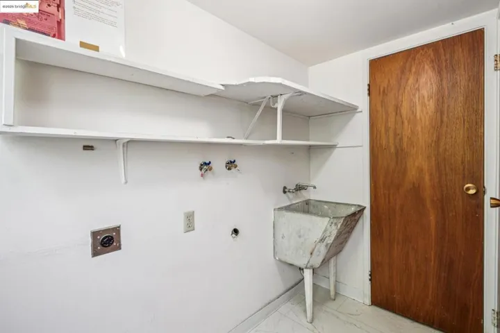 Washroom with hookup for an electric dryer, hookup for a washing machine, and light marble finish flooring