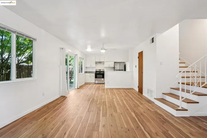 Unfurnished living room featuring stairs and light wood-style floors