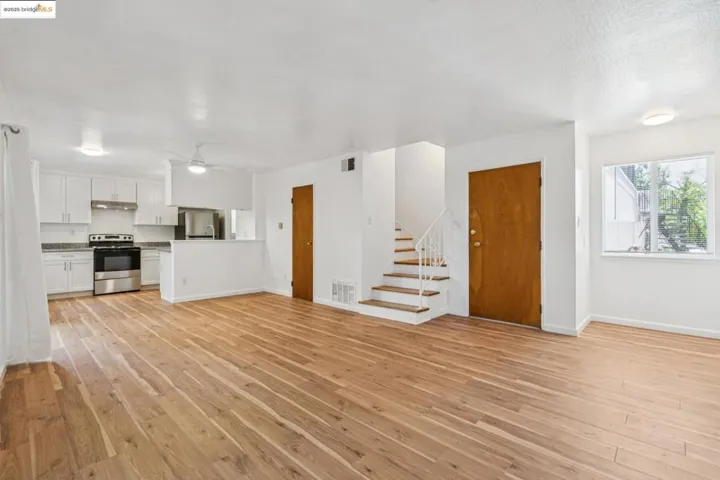 Unfurnished living room with light wood-type flooring, stairway, and ceiling fan