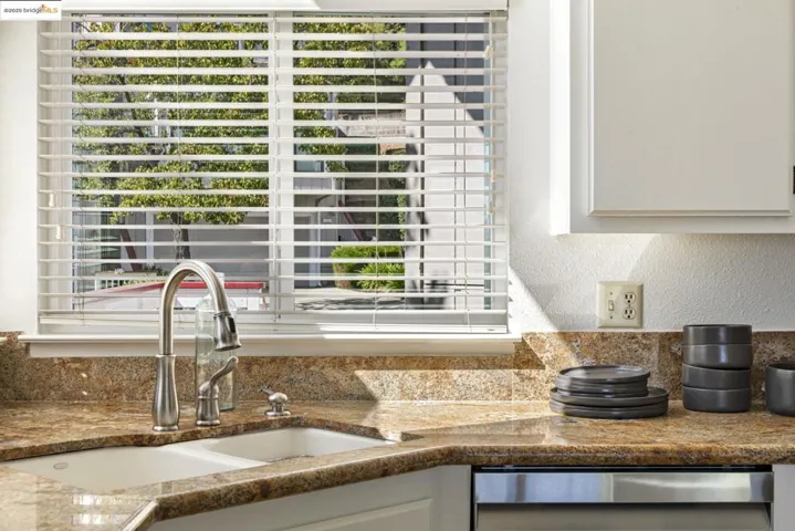 Kitchen with a textured wall, dishwasher, and white cabinets
