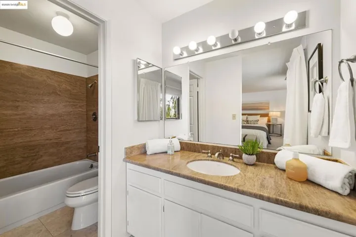 Bathroom featuring vanity, washtub / shower combination, connected bathroom, and tile patterned flooring