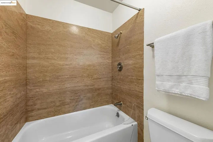 Bathroom featuring shower / tub combination and a textured wall