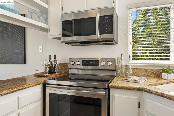 Kitchen with stainless steel appliances, white cabinets, and a textured wall