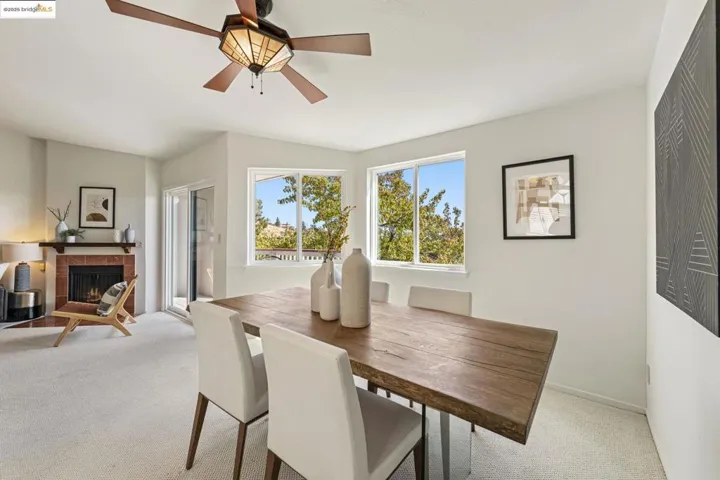 Dining area with light carpet, a tile fireplace, and a ceiling fan