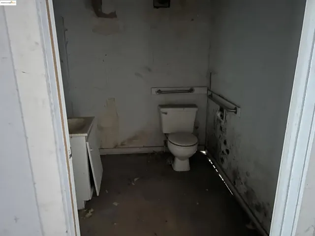 Half bath with vanity and unfinished concrete flooring