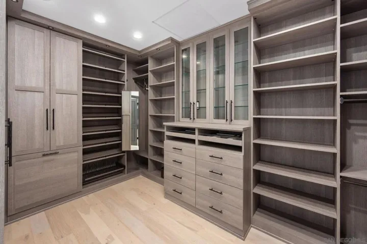 Her walk in closet with handbag storage behind glas cabinets, lined jewelry drawers , shoe display etc