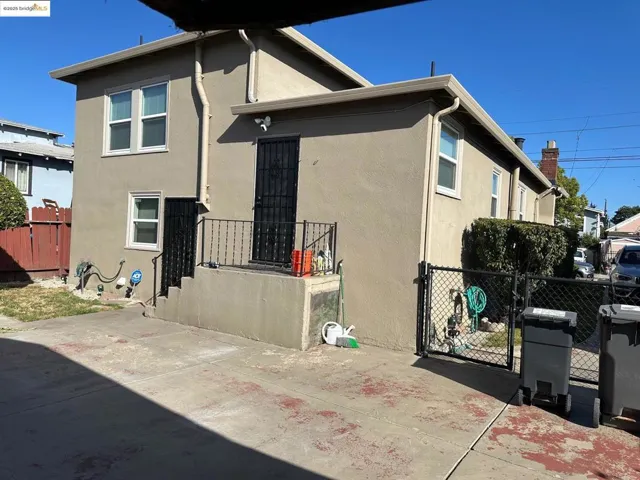 Back of house featuring stucco siding and a gate