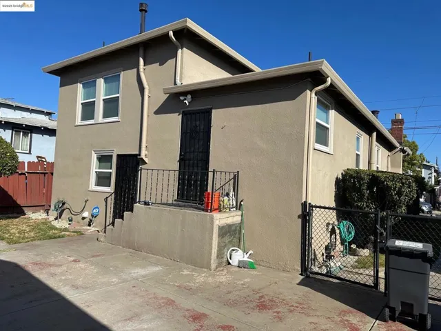 Back of house with stucco siding, a gate, and a patio area