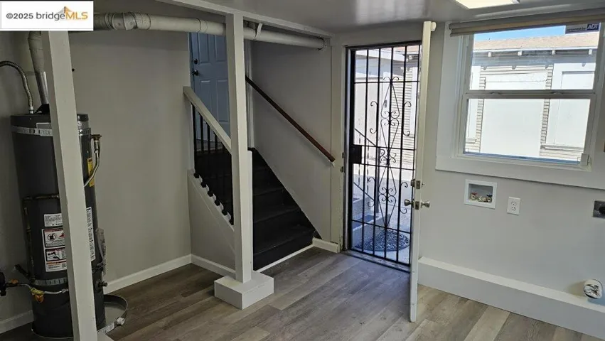 Foyer with wood finished floors, strapped water heater, and stairway