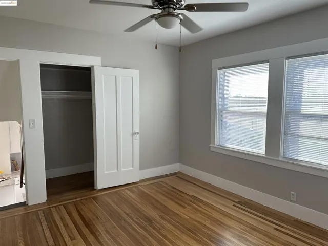 Unfurnished bedroom featuring wood finished floors, a closet, and a ceiling fan