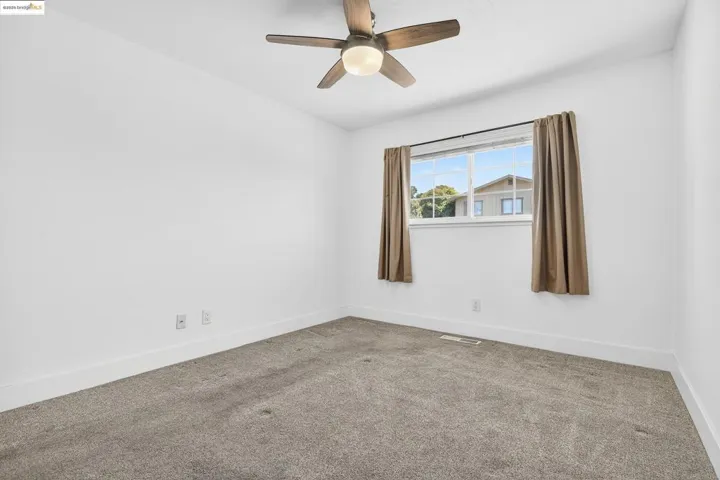 Carpeted spare room with a ceiling fan and baseboards