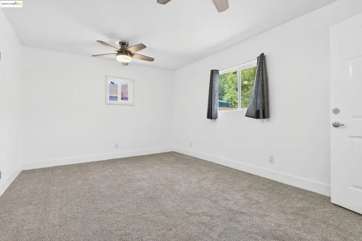 Empty room featuring ceiling fan and carpet floors