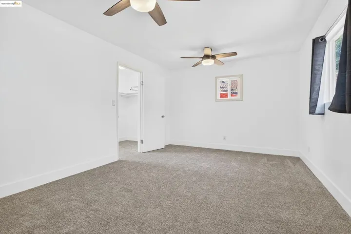 Carpeted spare room with ceiling fan and baseboards