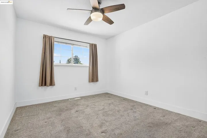 Carpeted spare room with baseboards and a ceiling fan