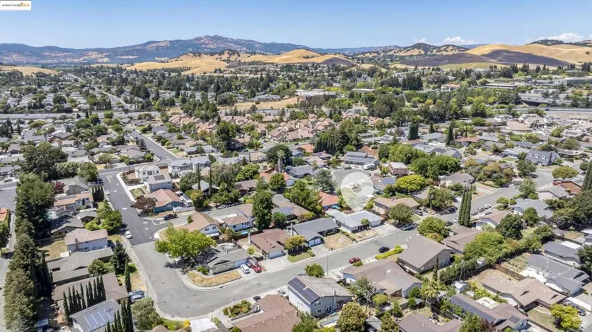 Aerial view of property and surrounding area featuring mountains and nearby suburban area
