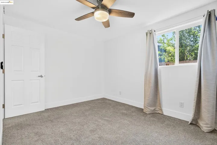 Carpeted spare room featuring a ceiling fan and baseboards