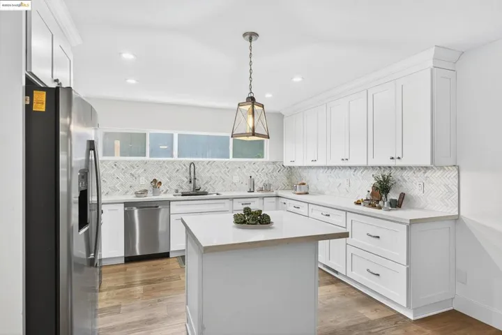 Kitchen featuring appliances with stainless steel finishes, light countertops, backsplash, white cabinetry, and recessed lighting