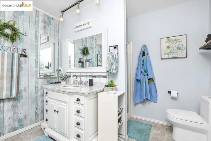Full bathroom with track lighting, vanity, a stall shower, and tile patterned flooring