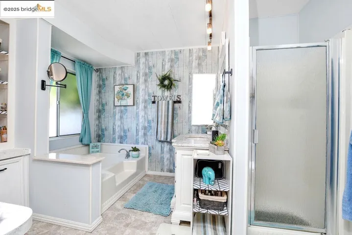 Bathroom with a shower stall, a garden tub, wallpapered walls, and vanity