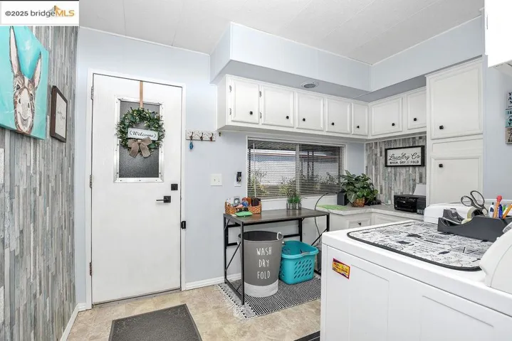 Kitchen featuring washer / dryer, white cabinets, light countertops, and light tile patterned floors