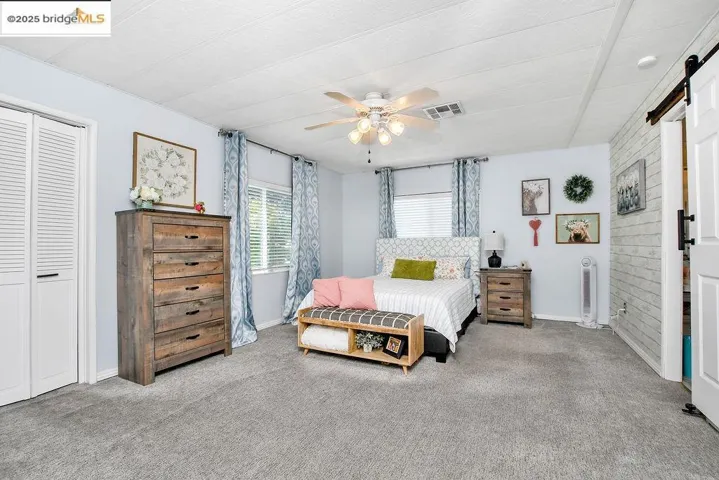 Bedroom featuring a barn door, carpet floors, a closet, and a ceiling fan