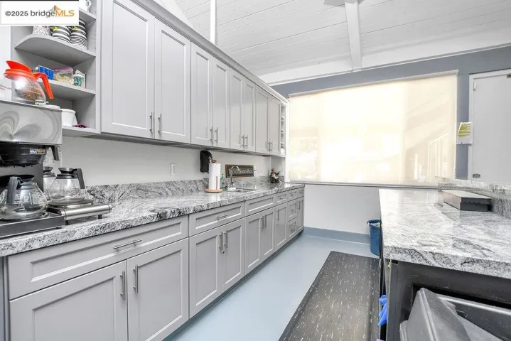 Kitchen featuring concrete flooring, open shelves, and beam ceiling