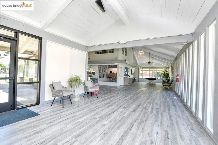 Sunroom featuring wood finished floors, high vaulted ceiling, a wooden ceiling with exposed beams, and a ceiling fan