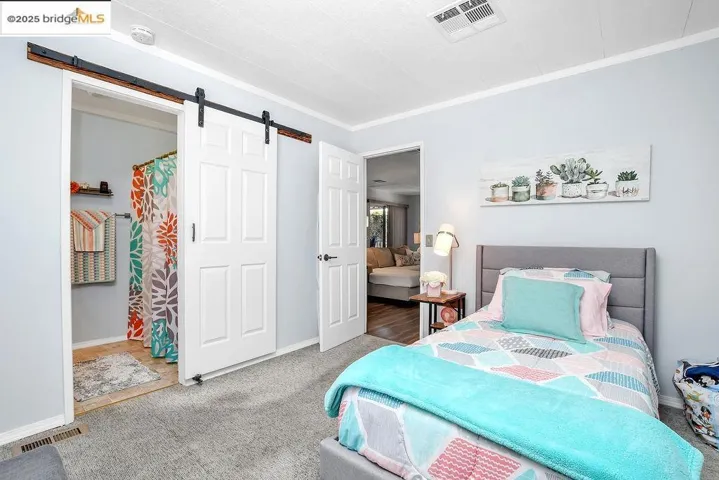 Carpeted bedroom featuring a barn door and ornamental molding