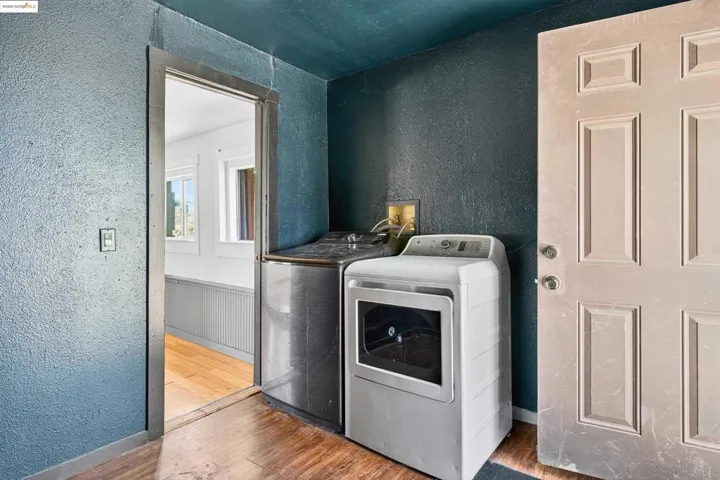 Laundry room with separate washer and dryer, wood finished floors, and a textured wall