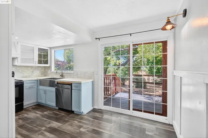Kitchen with decorative backsplash, light countertops, dishwasher, dark wood-type flooring, and black / electric stove