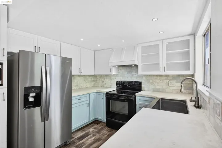 Kitchen with stainless steel fridge with ice dispenser, electric range, white cabinets, custom range hood, and recessed lighting